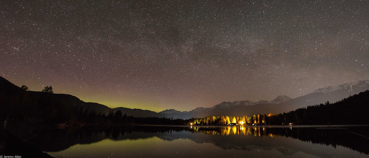 Milky Way reflecting on a still alpine lake under a starry night sky