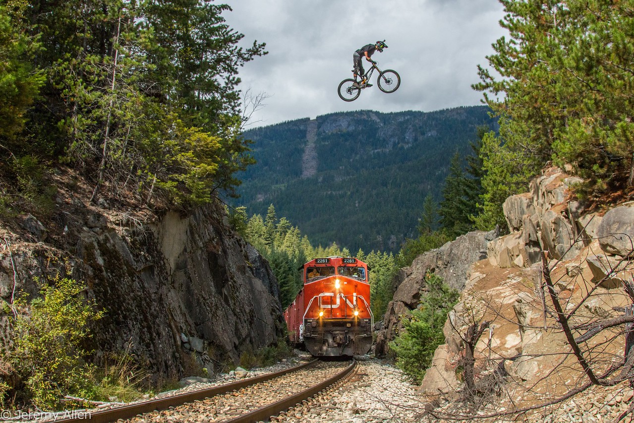 Mountain biker jumping over a moving train at sunset in Squamish, BC
